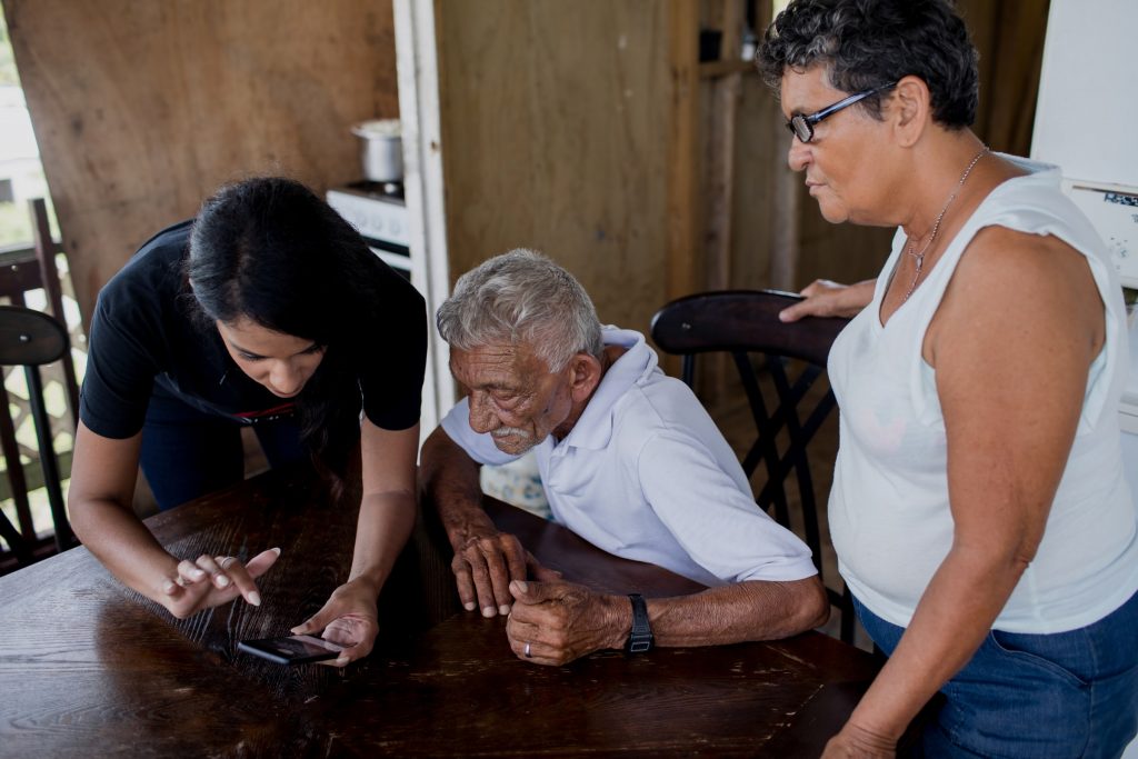A woman showing an elderly man how to use a cell phone